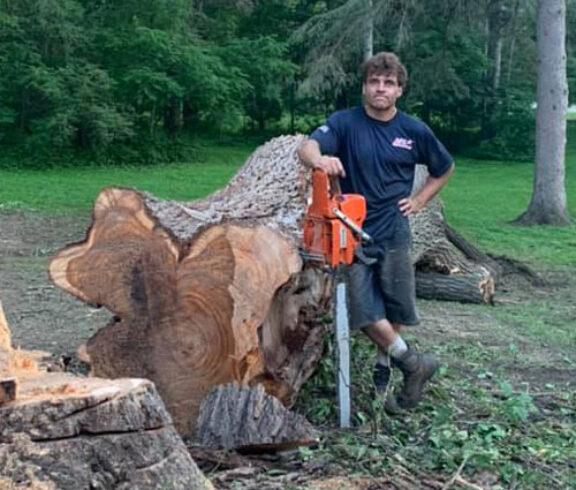 Tree Top climber employee standing beside cut tree